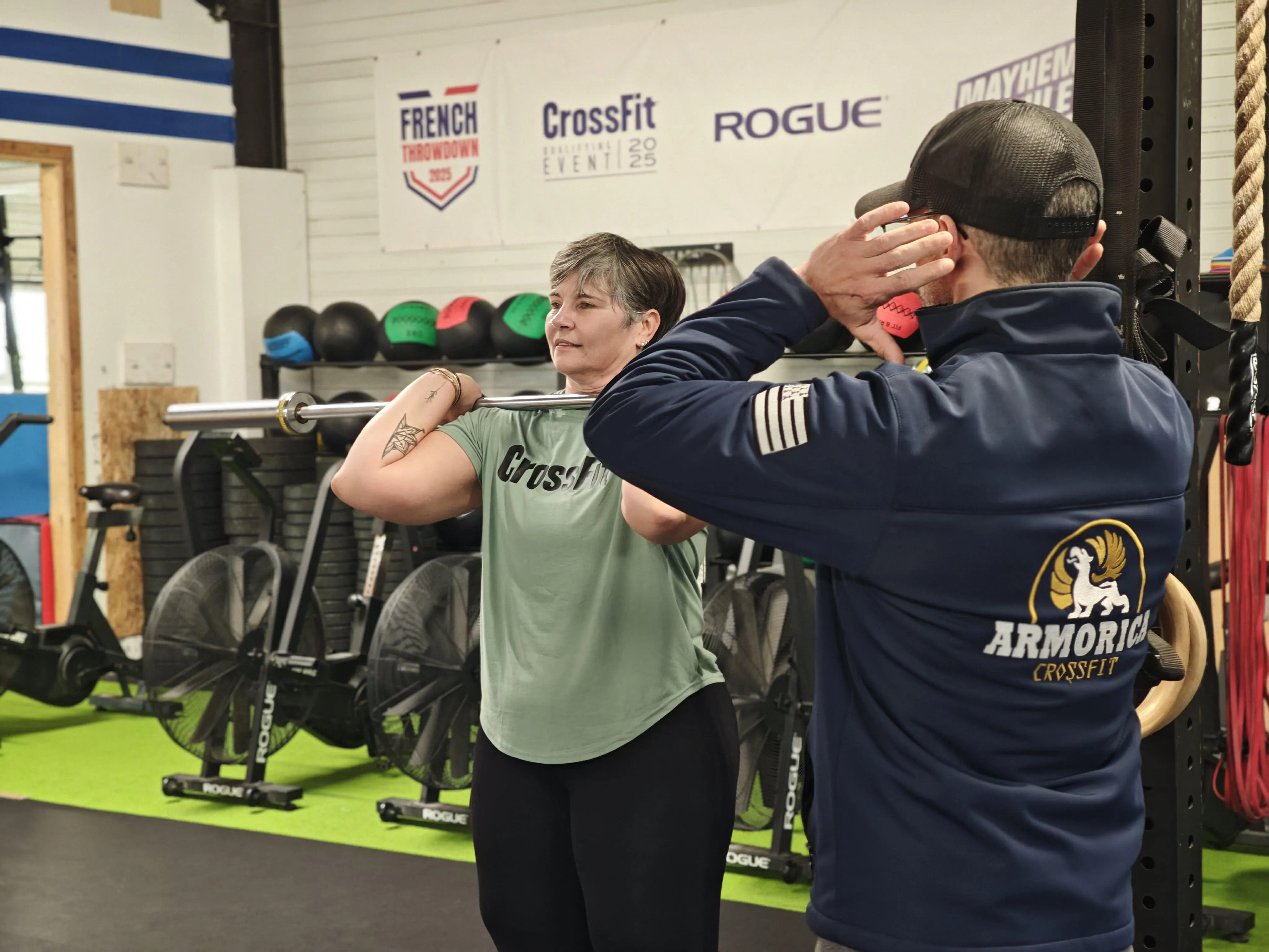 Un coach de CrossFit Armorica en train de coacher une adhérente sur son mouvement d'haltérophilie